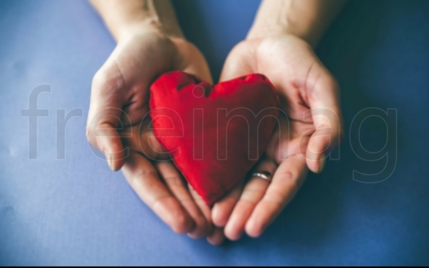 Dos manos  sostienen un corazón rojo sobre un fondo azul