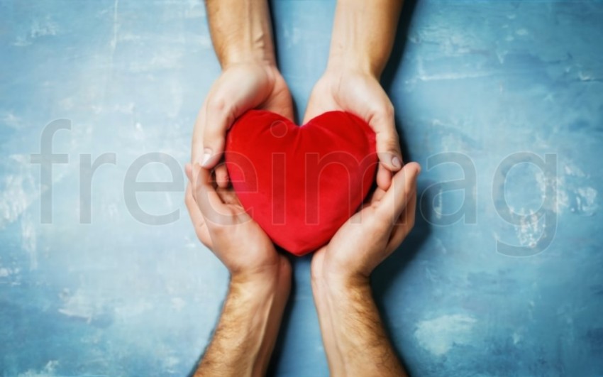 Dos manos  sostienen un corazón rojo sobre un fondo azul