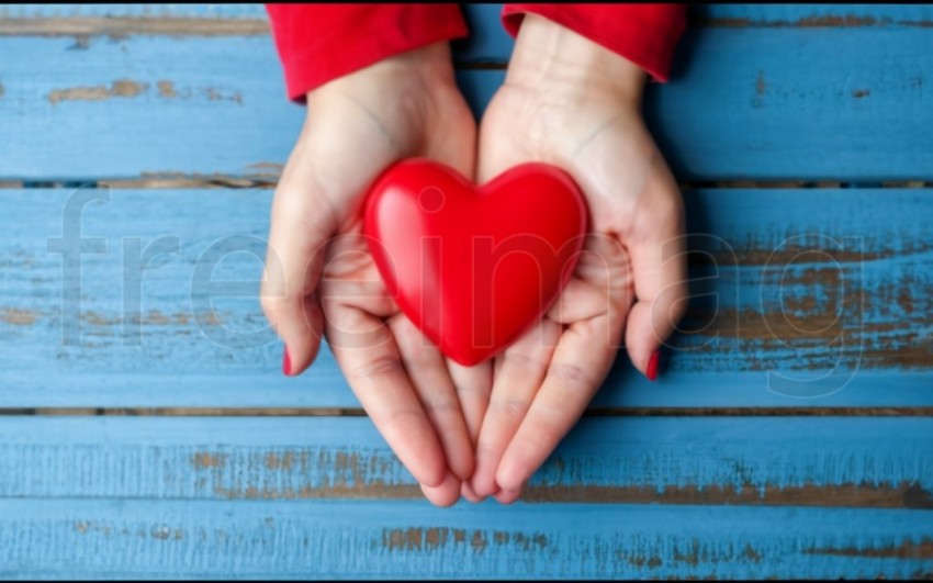 Dos manos  sostienen un corazón rojo sobre un fondo azul