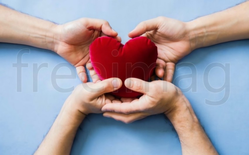 Dos manos  sostienen un corazón rojo sobre un fondo azul