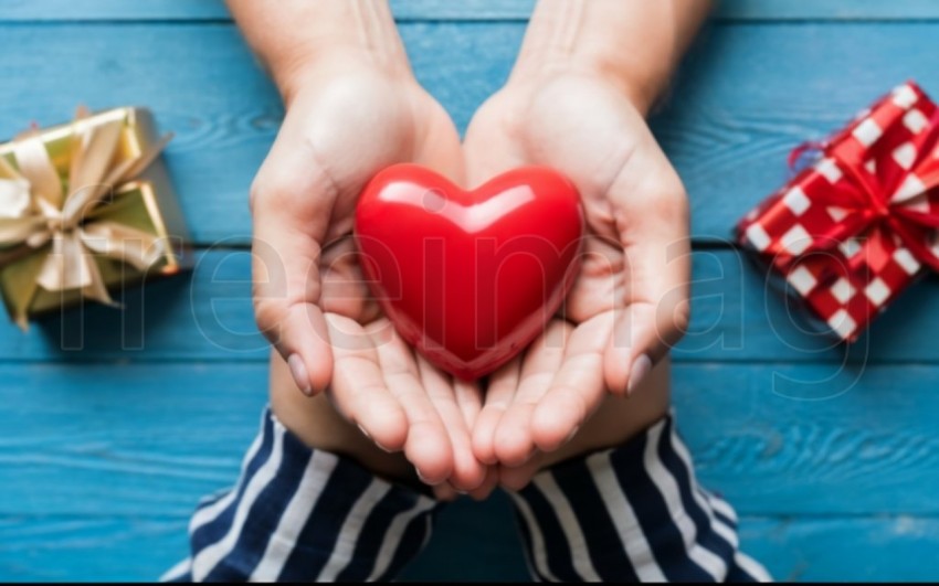 Dos manos  sostienen un corazón rojo sobre un fondo azul